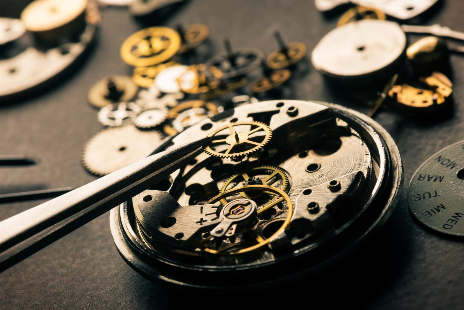 Componenti smontati di un orologio meccanico appoggiati su un panno da lavoro